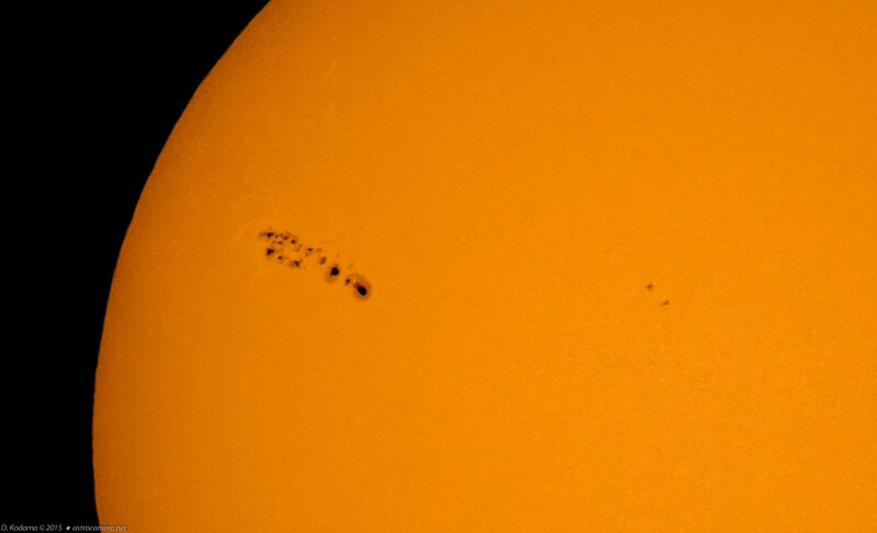Solar surface photograph showing sunspots and solar features against bright yellow-orange disk.