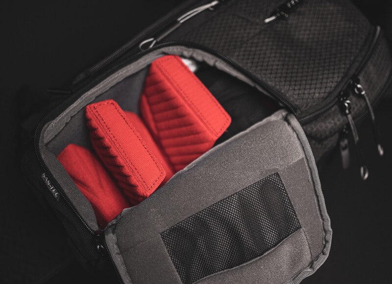 Open camera bag with red padded lens cases and protective dividers on dark background.