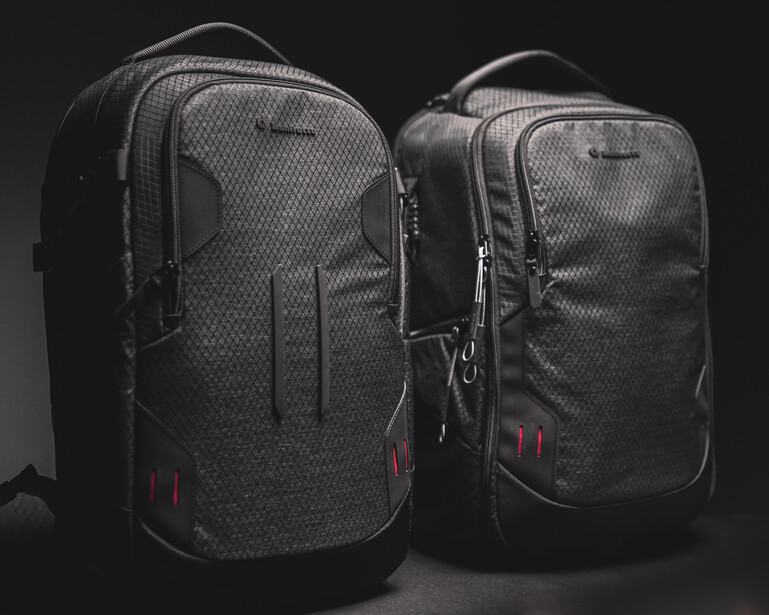 Two black camera backpacks with padded compartments displayed side by side against a dark background.