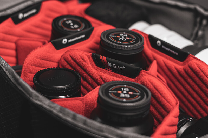 Camera lenses and accessories organized in a red padded case with black foam insert.