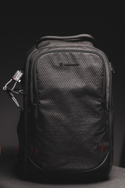 Black camera backpack with padded compartments and side carry handle against dark background.