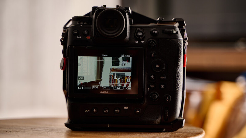 Professional mirrorless camera displaying live view footage on its rear LCD screen, positioned on a wooden surface.