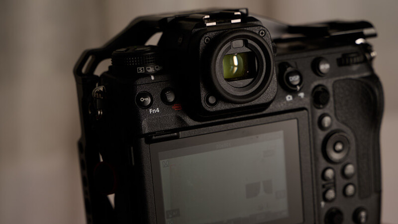 Close-up of a professional DSLR camera body showing the lens, LCD screen, and control buttons.