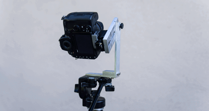 A black engine mounted on an adjustable vertical stand against a white sky backdrop.