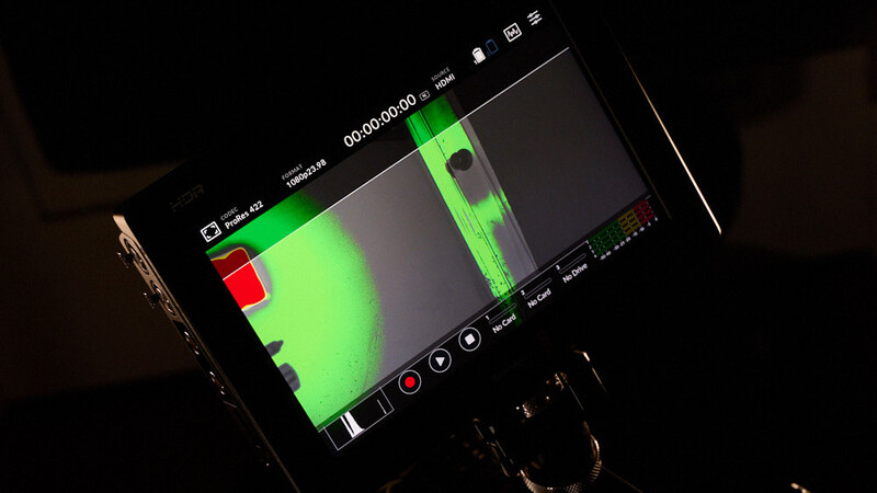 Thermal imaging monitor displaying green and red heat signature footage with timecode and interface controls.