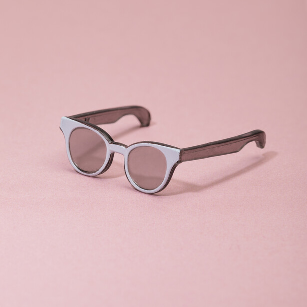 Pair of sunglasses with translucent light blue frames and dark brown arms on a pink background.