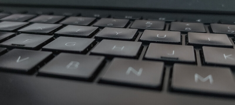 Close-up of a dark laptop keyboard with shallow depth of field, focusing on the center keys with blurred keys in foreground and background.