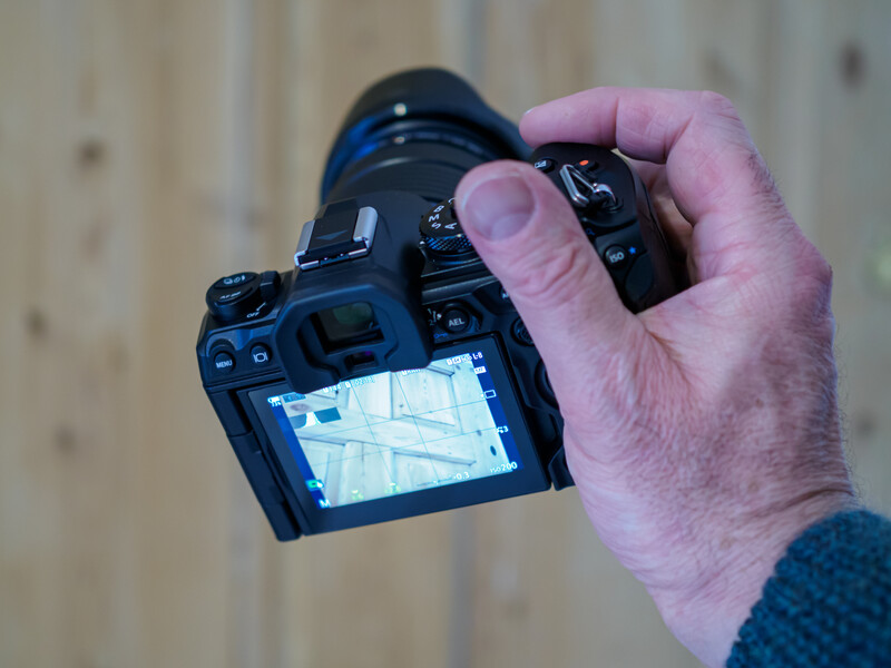 Photographer holding a DSLR camera displaying a thermal or infrared image on its rear LCD screen.