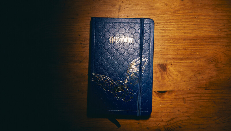 Navy blue hardcover notebook with quilted pattern and elastic band closure on wooden surface.