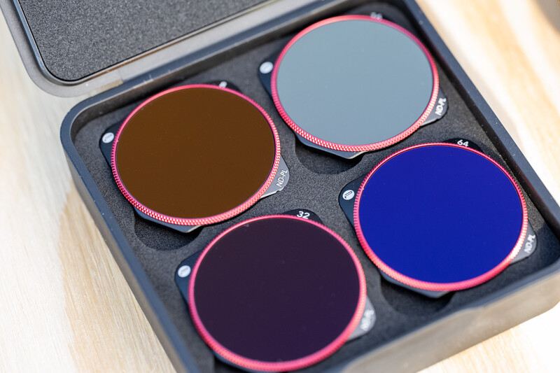 Set of four circular optical filters with pink frames arranged in a foam-lined case.