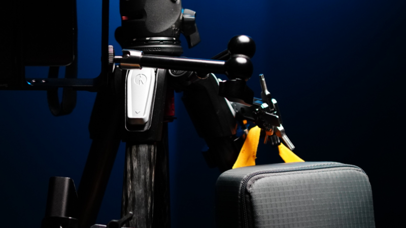 Studio product photography setup with electric scooter and luggage against deep blue backdrop.