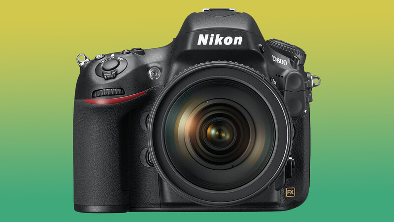 Nikon D800 DSLR camera with attached zoom lens against a gradient yellow-to-green background.