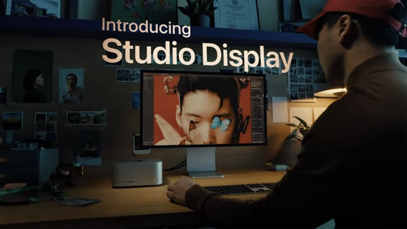 Creative professional working at desk with monitor displaying Studio Display introduction presentation.
