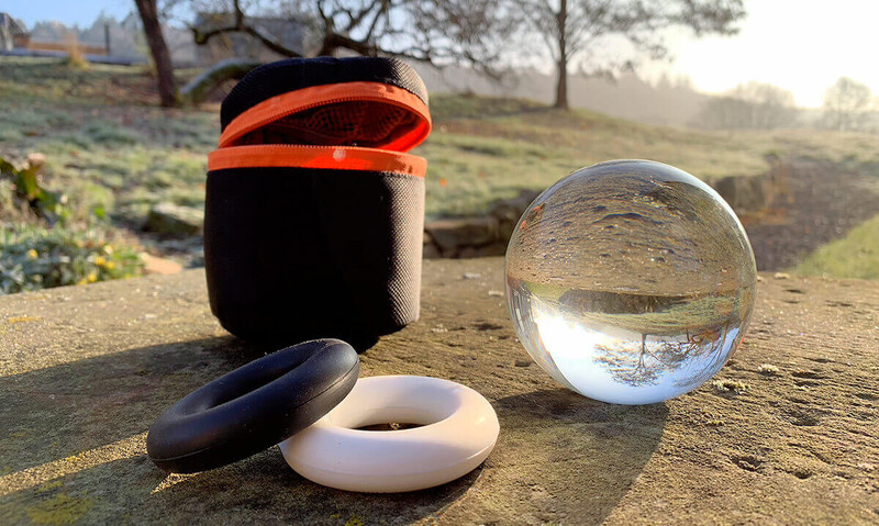 Crystal lens ball and lens accessories arranged on dirt ground with rural landscape and trees in background.