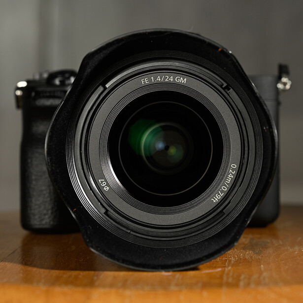 Mirrorless camera with standard zoom lens mounted, viewed head-on on wooden surface.
