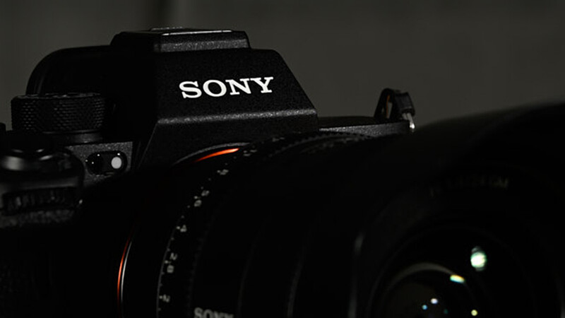 Sony camera body in dramatic side lighting against a dark background.