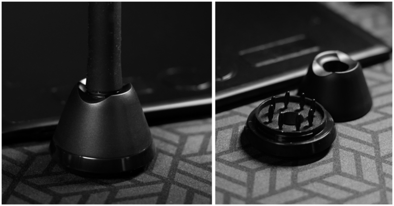 Black microphone stand base and shock mount on patterned surface in studio lighting.