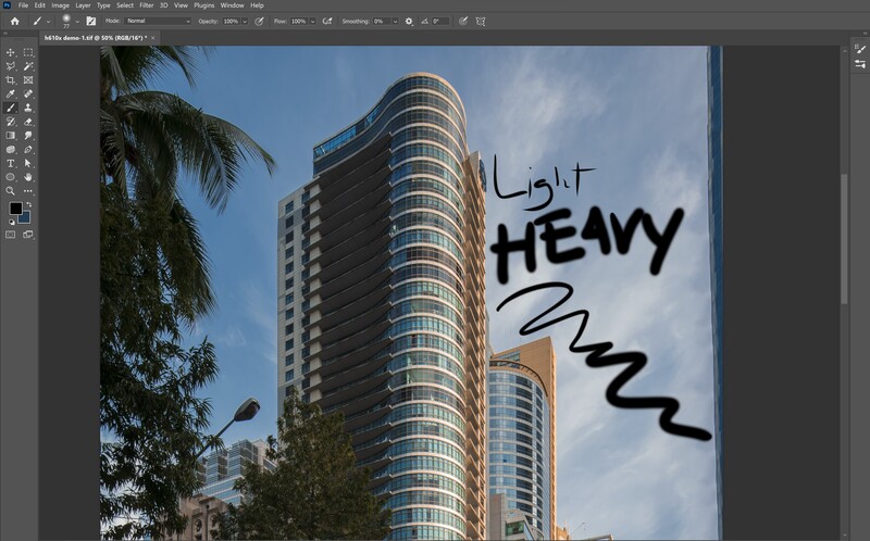 Modern curved high-rise residential building with blue-tinted glass facade and palm trees, overlaid with black handwritten text reading "LIGHT," "HEAVY," and an arrow.