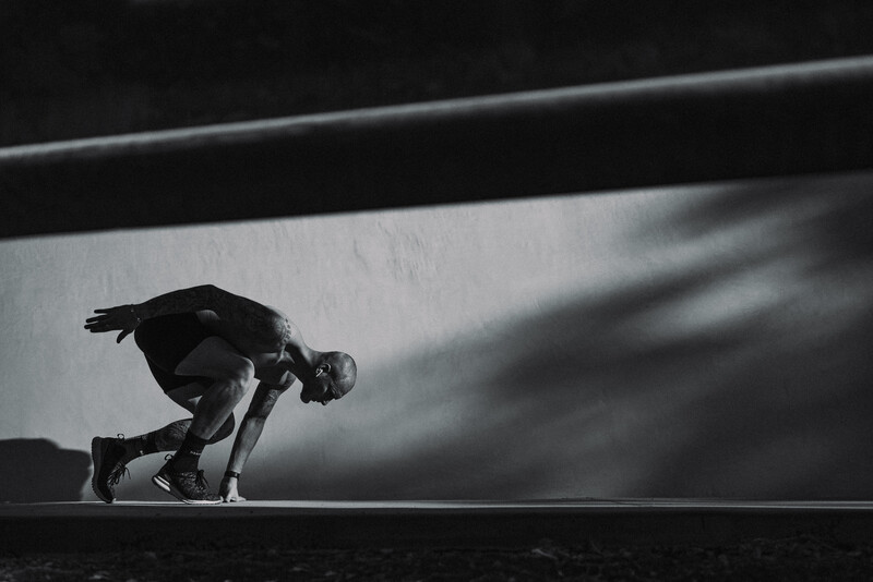Silhouetted figure in crouched position on a geometric platform against dramatic lighting.