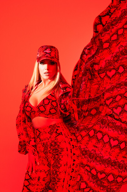 Woman in red patterned outfit and matching cap against monochromatic red background.