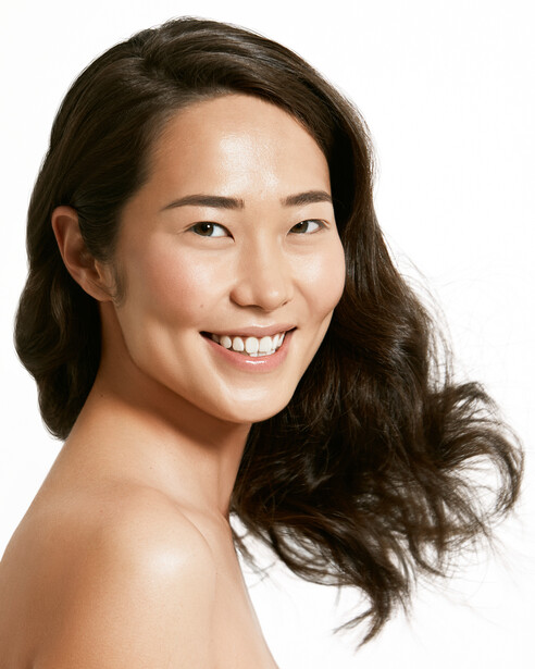 Woman with shoulder-length dark hair smiling at camera against white background.