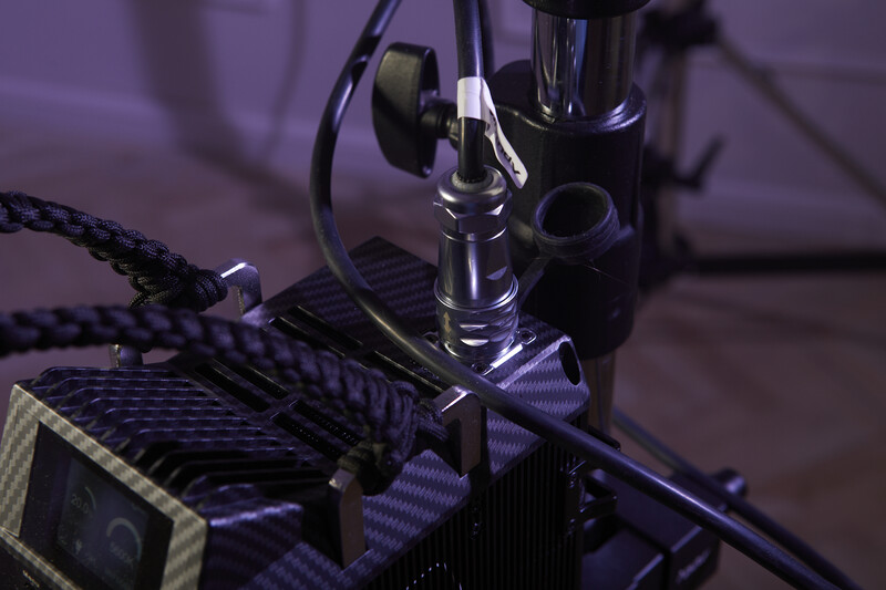 Close-up of a 3D printer nozzle and heated bed assembly with purple ambient lighting.