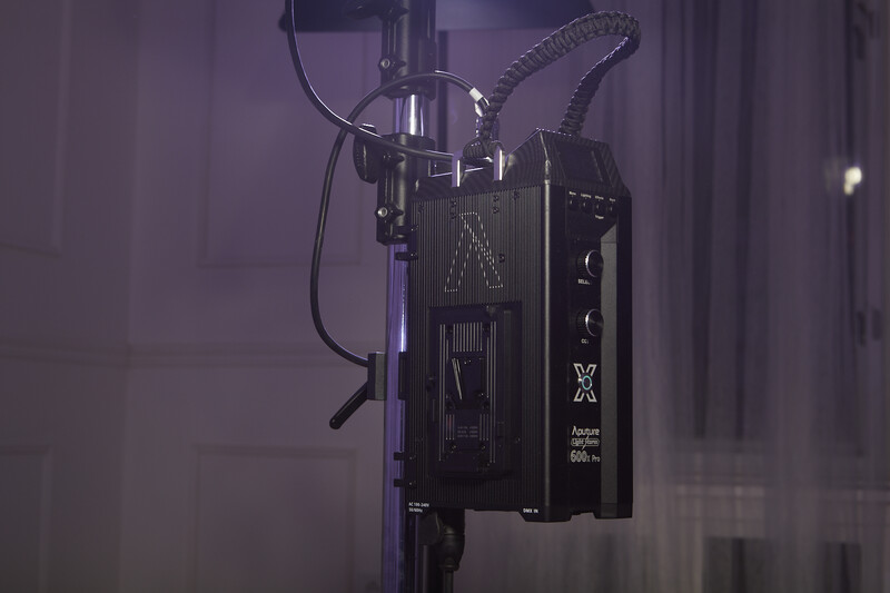 Professional cinema camera mounted on a rig with articulating arms and cables against a purple-tinted backdrop.