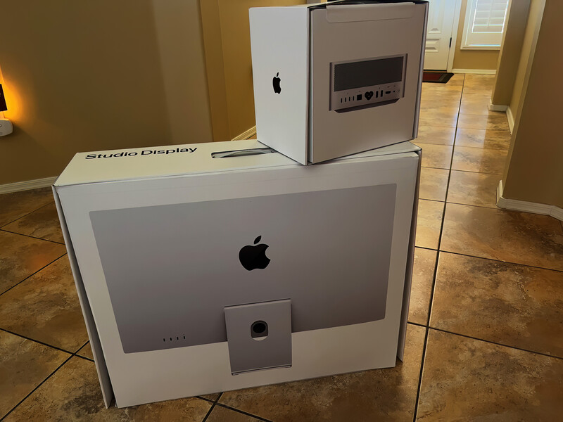 Apple Studio Display monitor and Mac Studio tower displayed on a tile floor in a home interior.