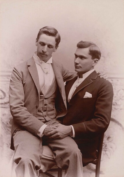 Two men in formal suits posed together for a studio portrait, circa early 20th century.