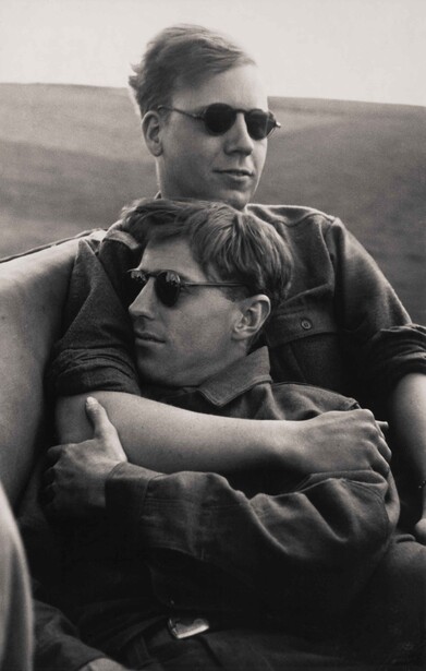 Two men wearing sunglasses pose together outdoors in black and white.