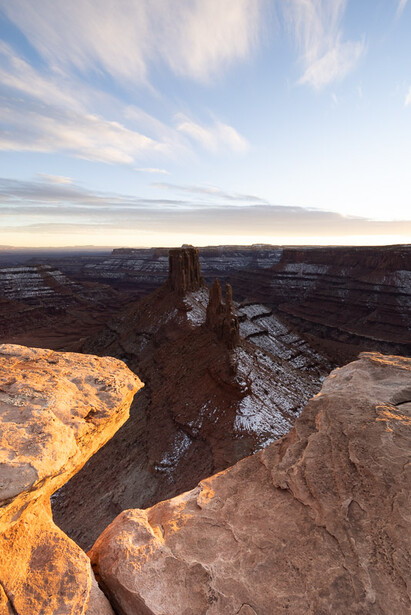 Rock formation rising from a canyon landscape during golden hour with dramatic sky overhead.