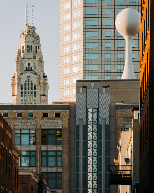 Contrasting architectural styles with ornate historic tower flanked by modern glass and steel buildings.