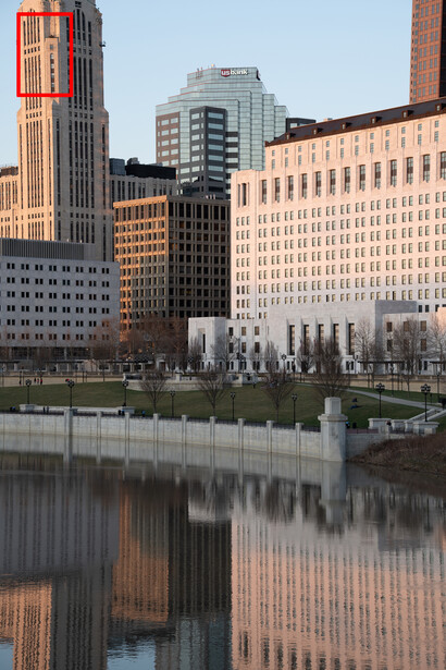 Urban skyline reflected in still water with brick and glass buildings at golden hour.