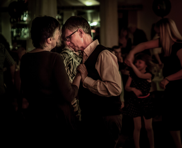 Two men dancing together at an indoor evening event with warm ambient lighting.