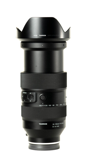 Black telephoto lens with hood attached, showing focus and aperture rings against white background.