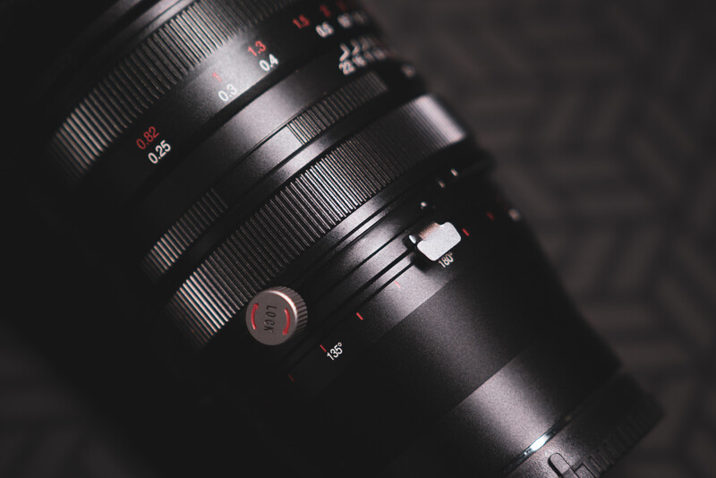 Close-up of a telephoto lens barrel showing focus and aperture rings against a dark background.