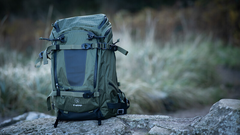 Gray hiking backpack positioned on a rock with blurred wilderness background.