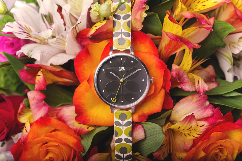 Watch with black face and patterned band centered on colorful fresh flowers.