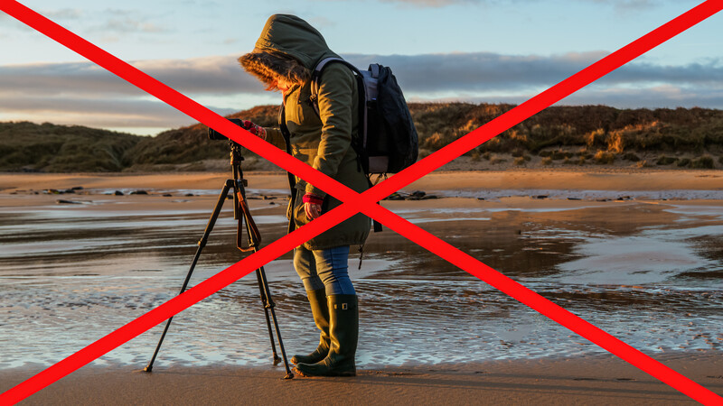 Illustration showing a photographer with tripod and camera on a beach, marked with a red X.