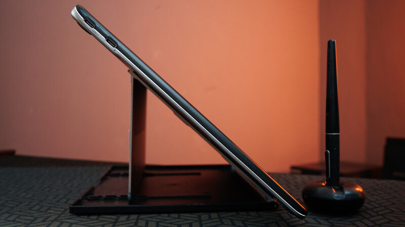 Smartphone leaning against a stand with warm backlighting and studio setup visible behind it.