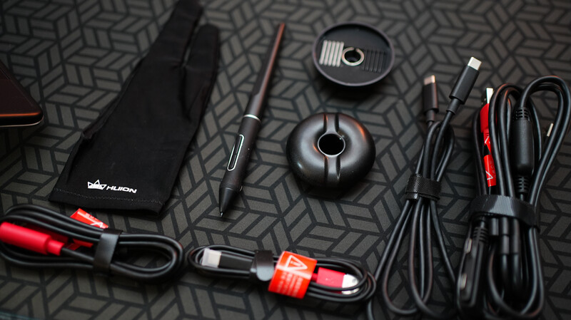 Professional audio and video equipment laid out on a geometric patterned surface, including microphone, cables, and accessories.