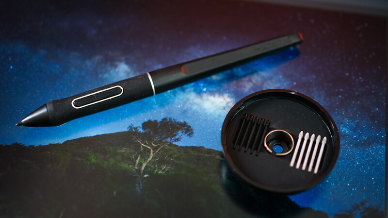 Digital stylus pen and graphics tablet on a landscape photograph with starry sky background.