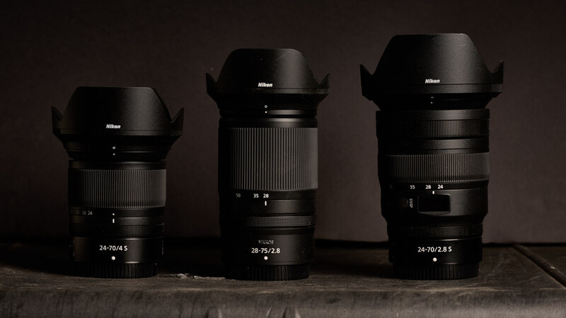 Three Nikon Z-mount lenses arranged side by side with lens hoods extended, labeled 24-70/4.5, 28-75/2.8, and 24-70/2.8 S.