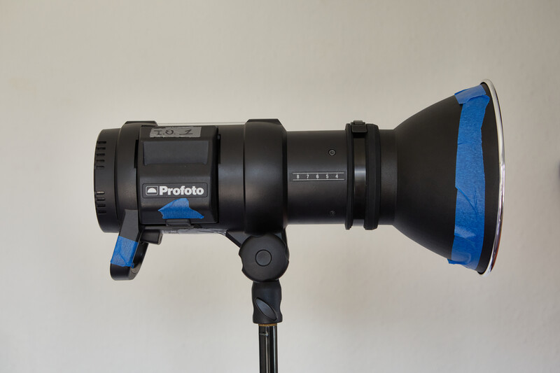 Profoto studio monolight with blue reflector mounted on stand against neutral background.