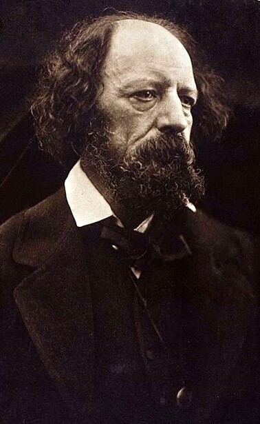 Portrait of a bearded man with shoulder-length hair in dark formal attire against a dark background.