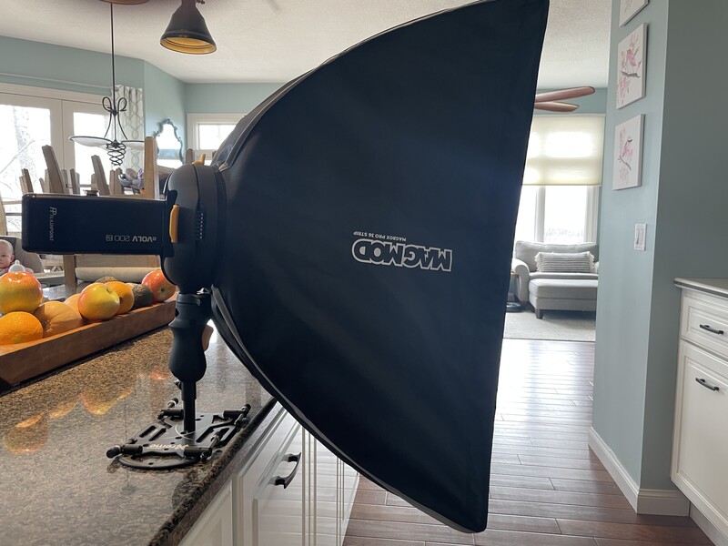 Large black softbox light modifier mounted on a stand in a home studio setting.