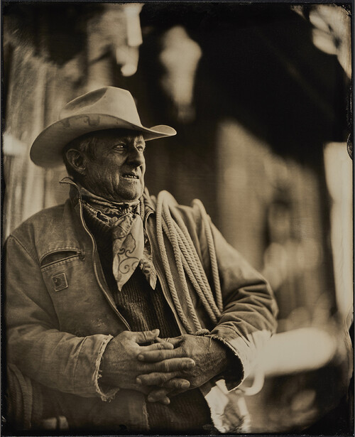 Weathered older man in cowboy hat and western attire gazes to the side.