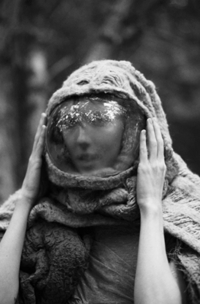 Person wearing a headscarf with face obscured by a reflective spherical object.