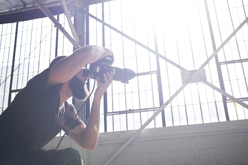 Photographer shooting upward inside a modern concrete structure with geometric skylight framework.