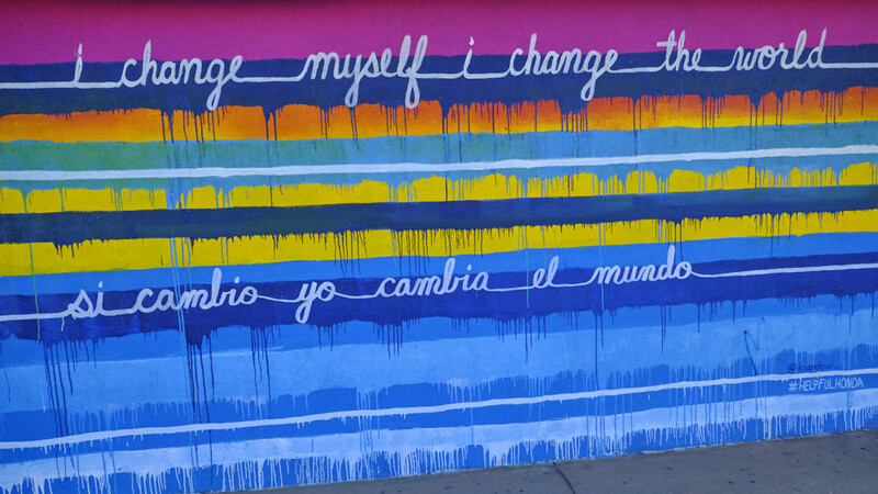 Street mural with colorful horizontal bands and audio waveform visualizations with inspirational text overlays.